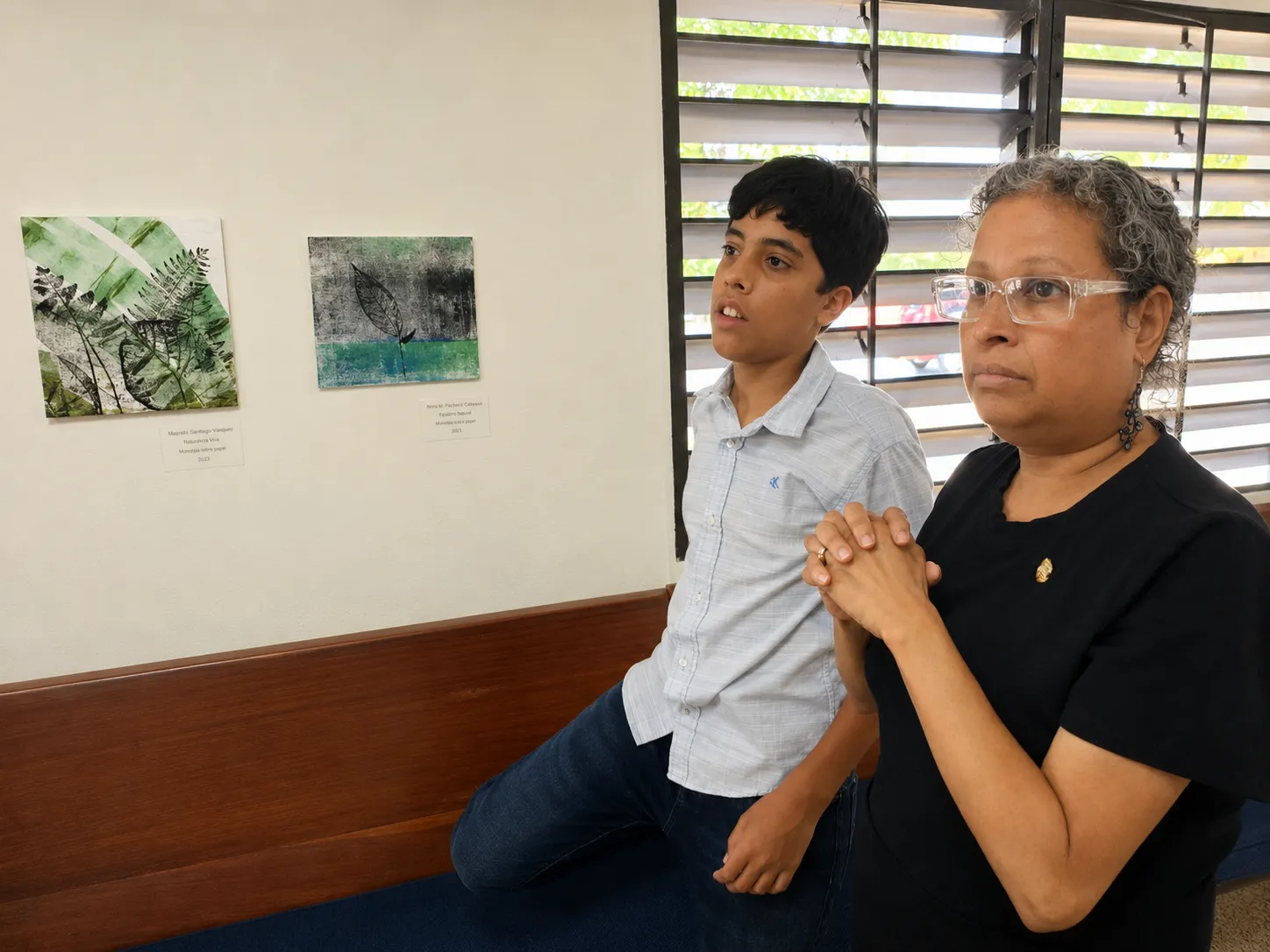 La Profa. Areli M. Nieves Montañez y Urayoán observan las obras durante la exposición