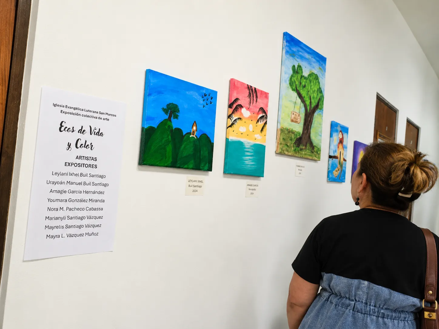 Cartel de Ecos de Vida y Color junto a varias obras presentadas en la exposición